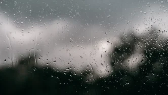 Gotas de lluvia cayendo sobre una ventana con un fondo nublado en Londres