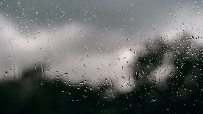 Gotas de lluvia cayendo sobre una ventana con un fondo nublado en Londres