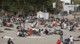 Numerosos migrantes descansando en una playa de Ceuta tras la llegada masiva a través de la frontera.