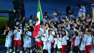 Delegación de atletas mexicanos celebrando con la bandera de México en los Juegos Centroamericanos y del Caribe.