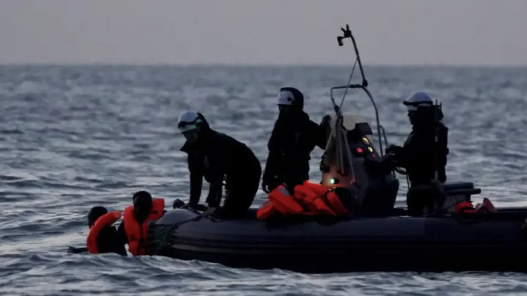 Equipos de rescate y seguridad operando en una pequeña embarcación con migrantes en alta mar.