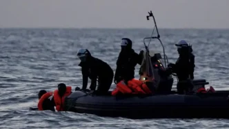 Equipos de rescate y seguridad operando en una pequeña embarcación con migrantes en alta mar.
