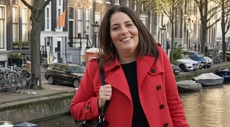 Nicole Beling sonriendo con un abrigo rojo frente a un canal