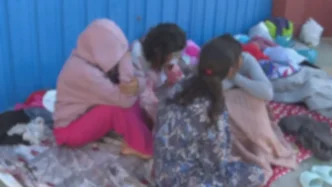 Menores migrantes sentadas en el suelo en una zona exterior de Ceuta