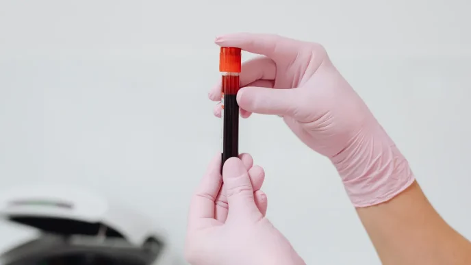 Persona con guantes protectores sosteniendo un tubo de ensayo con muestra de sangre