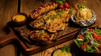 Tabla de madera con una parrillada mixta latinoamericana, chorizo, papas asadas y ensalada fresca