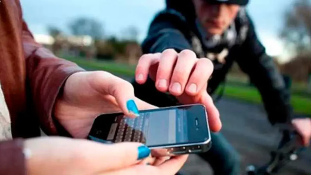 Ladrón en bicicleta intentando arrebatar un teléfono móvil a una persona en la calle