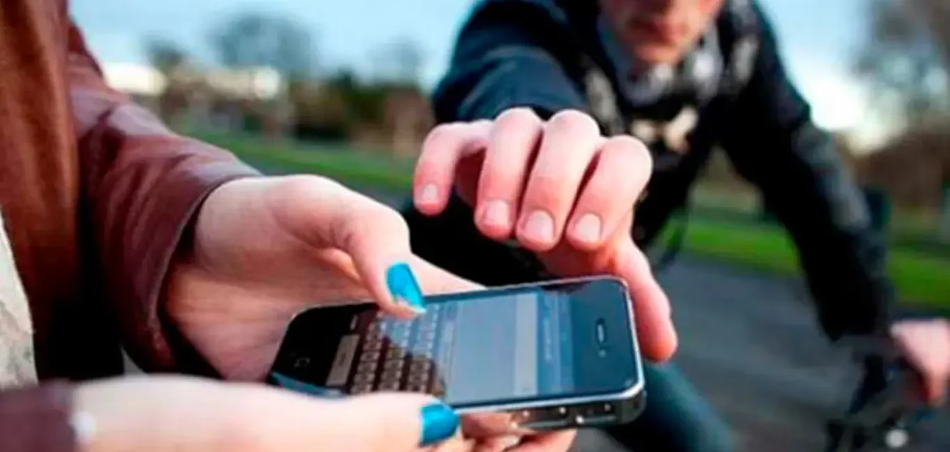 Ladrón en bicicleta intentando arrebatar un teléfono móvil a una persona en la calle