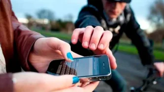 Ladrón en bicicleta intentando arrebatar un teléfono móvil a una persona en la calle