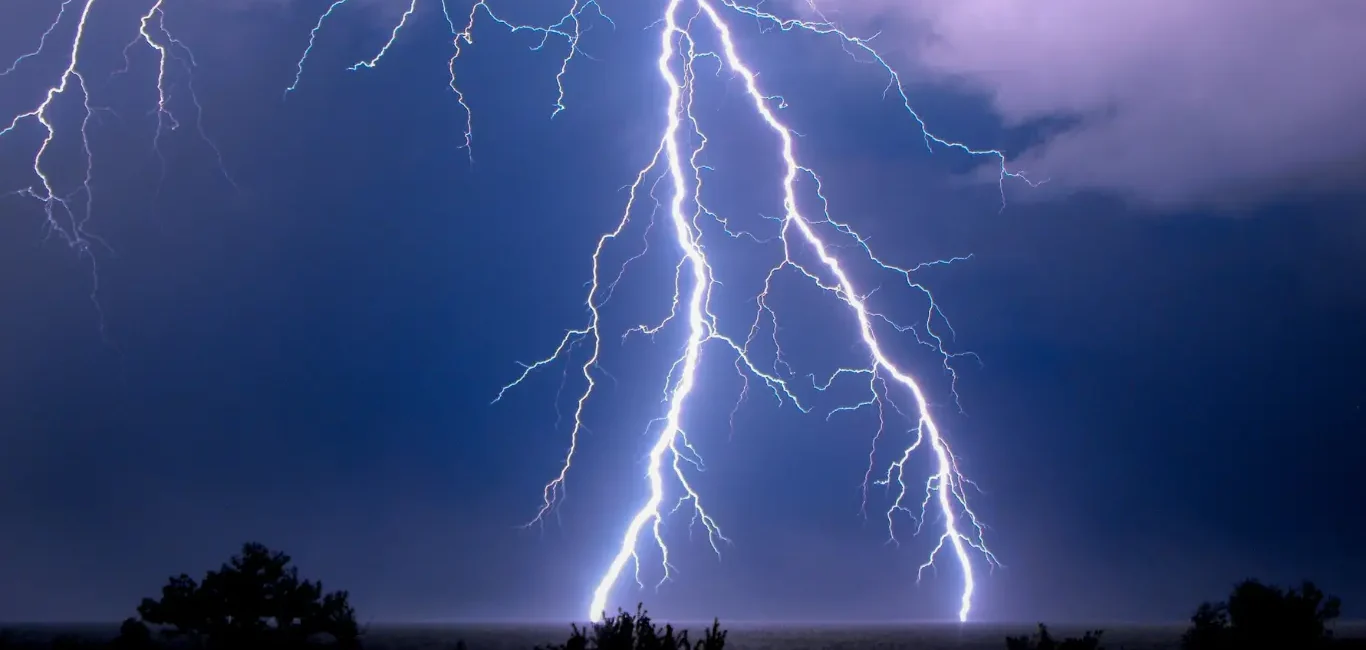 Potentes rayos de tormenta eléctrica cruzando el cielo oscuro nocturno sobre el horizonte