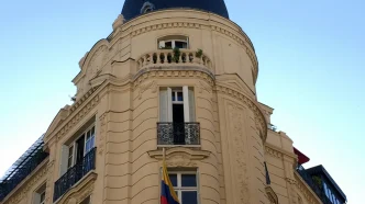 Fachada de un edificio de arquitectura clásica en París con el escudo y la bandera de Colombia en un balcón