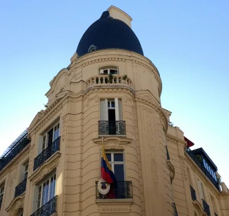 Fachada de un edificio de arquitectura clásica en París con el escudo y la bandera de Colombia en un balcón