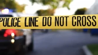 Cinta amarilla de precaución policial en la escena de un crimen con una patrulla al fondo