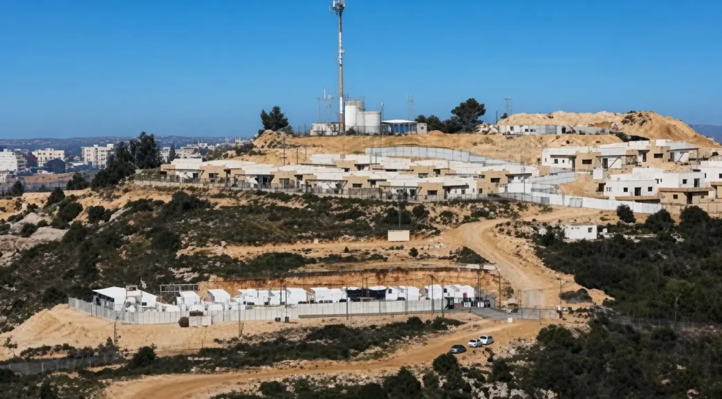 Vista panorámica de un asentamiento israelí con estructuras blancas y vallas sobre una colina en Cisjordania.