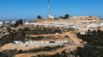 Vista panorámica de un asentamiento israelí con estructuras blancas y vallas sobre una colina en Cisjordania.