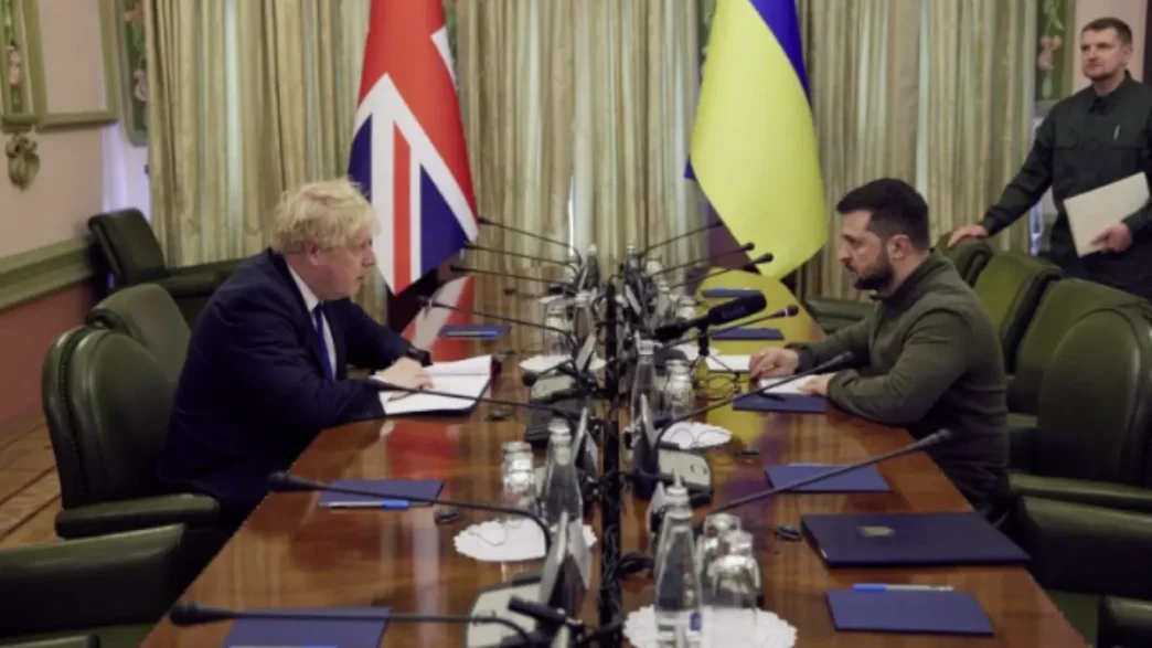 Boris Johnson reunido en una mesa de conferencias con Volodímir Zelenski junto a las banderas de Reino Unido y Ucrania.