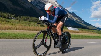 Ciclista Brandon McNulty acoplado en su bicicleta de contrarreloj vistiendo el uniforme de la selección de Estados Unidos.