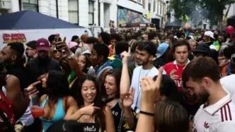 Multitud de asistentes celebrando y bailando festivamente en una calle durante el Carnaval de Notting Hill