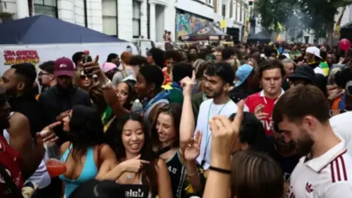 Multitud de asistentes celebrando y bailando festivamente en una calle durante el Carnaval de Notting Hill