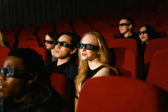 Espectadores en el interior de una sala de cine oscura usando gafas 3D para ver una película