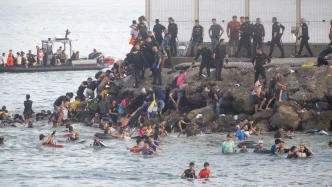 Agentes de las Fuerzas de Seguridad gestionando la llegada masiva de personas en el espigón fronterizo de Ceuta.