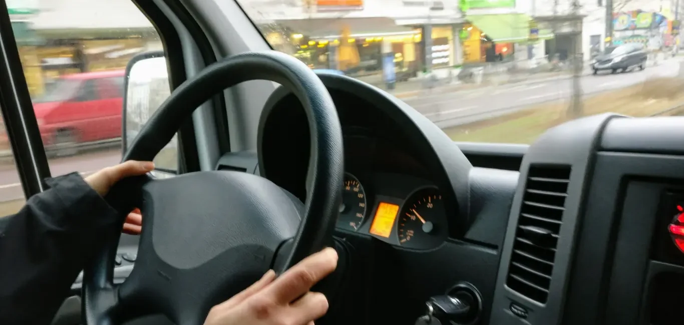 Persona al volante de un vehículo conduciendo por una calle del Reino Unido.
