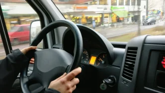 Persona al volante de un vehículo conduciendo por una calle del Reino Unido.