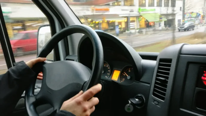 Persona al volante de un vehículo conduciendo por una calle del Reino Unido.