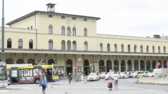 Fachada principal de la estación de tren de Augsburgo con autobuses y tráfico en el exterior