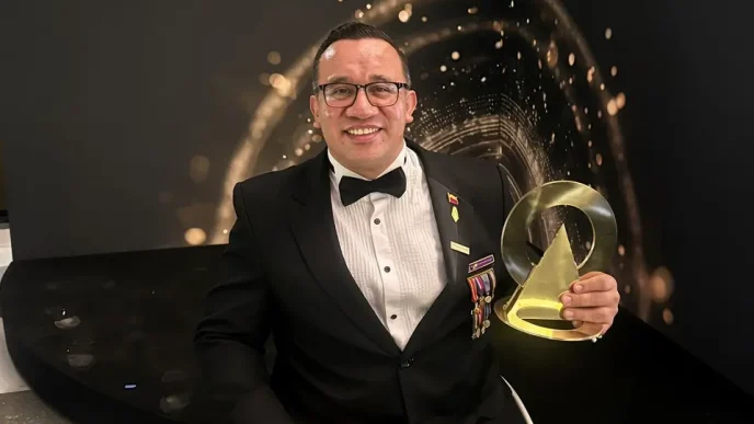 Francisco Pedraza sonriendo con su chaqueta oficial y bandera de Colombia tras recibir el galardón en Londres.