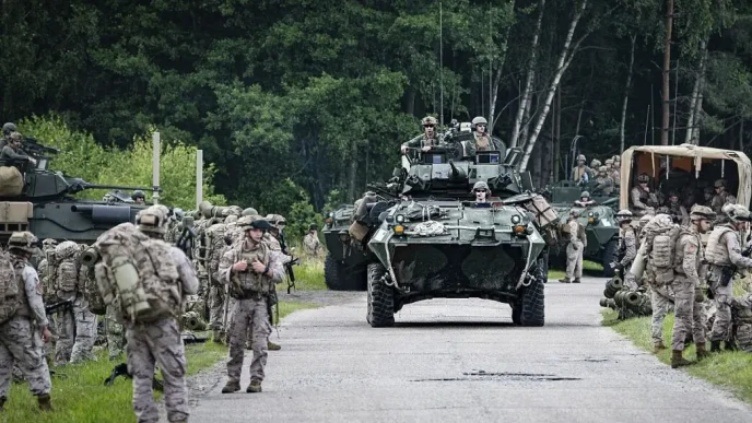 Tropas militares y vehículos blindados desplazándose durante un entrenamiento del ejército en una zona boscosa de Europa.