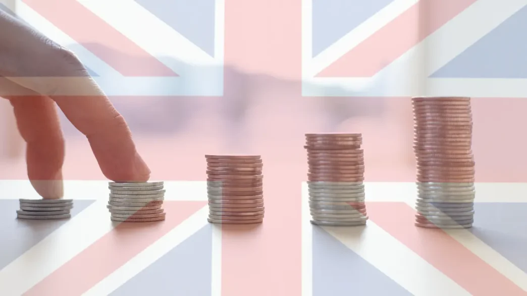 Pilas de monedas apiladas en orden ascendente sobre una bandera británica superpuesta.