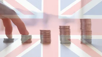 Pilas de monedas apiladas en orden ascendente sobre una bandera británica superpuesta.