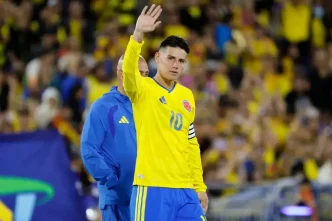 James Rodríguez vistiendo la camiseta amarilla número 10 de la Selección Colombia mientras saluda con la mano levantada al público en el estadio.