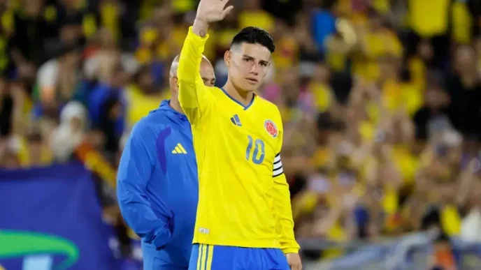 James Rodríguez vistiendo la camiseta amarilla número 10 de la Selección Colombia mientras saluda con la mano levantada al público en el estadio.