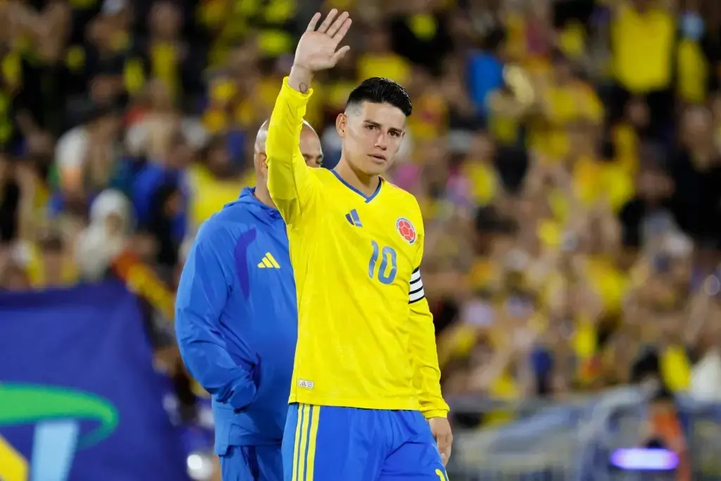 James Rodríguez vistiendo la camiseta amarilla número 10 de la Selección Colombia mientras saluda con la mano levantada al público en el estadio.