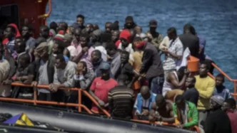 Grupo numeroso de migrantes a bordo de una embarcación de rescate en alta mar.