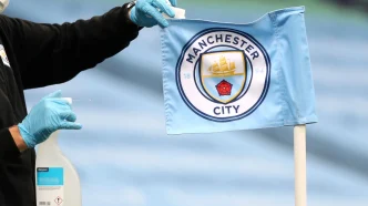 Banderín de córner con el escudo del Manchester City siendo desinfectado por un operario con guantes.