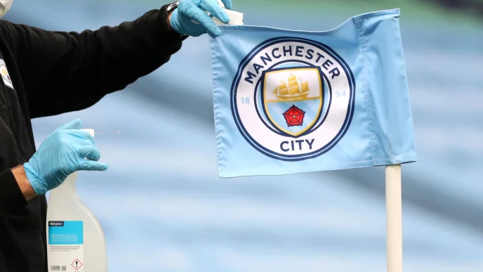 Banderín de córner con el escudo del Manchester City siendo desinfectado por un operario con guantes.
