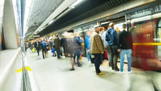 Pasajeros esperando en el andén e ingresando a un vagón del metro de Londres en una estación subterránea.