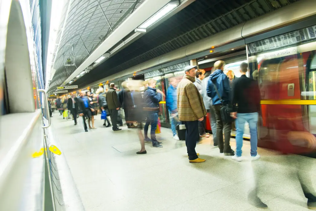 Pasajeros esperando en el andén e ingresando a un vagón del metro de Londres en una estación subterránea.