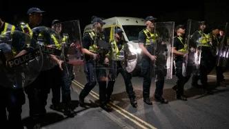 Agentes de policía británicos con escudos antidisturbios desplegados durante la noche en Portsmouth.