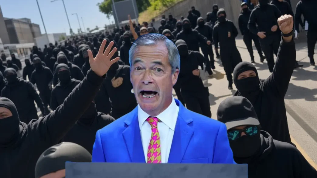 Nigel Farage hablando en primer plano con una multitud de manifestantes enmascarados de negro de fondo.