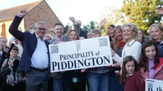 Vecinos del pueblo de Piddington levantando los puños y sosteniendo un cartel que dice Principality of Piddington.