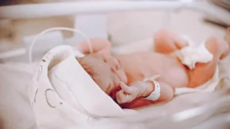 Bebé recién nacido acostado en una cuna de hospital con pulsera de identificación en la muñeca.