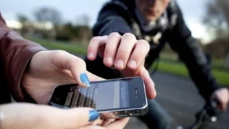 Un ladrón en bicicleta intenta arrebatar un teléfono móvil de las manos de una mujer en la calle.