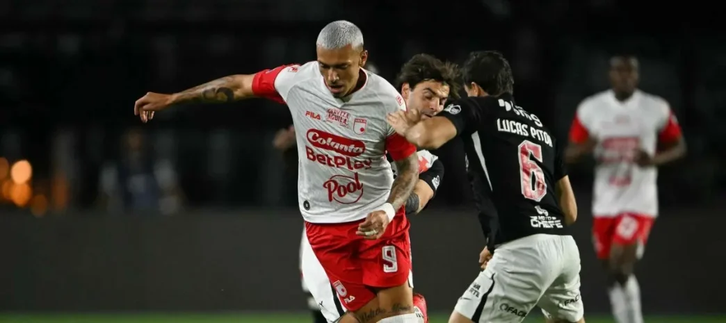 Un jugador de Independiente Santa Fe disputando el balón de espaldas contra un defensor de Vasco da Gama.