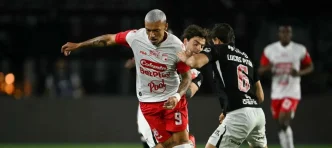 Un jugador de Independiente Santa Fe disputando el balón de espaldas contra un defensor de Vasco da Gama.