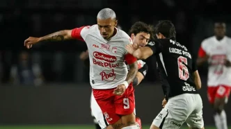 Un jugador de Independiente Santa Fe disputando el balón de espaldas contra un defensor de Vasco da Gama.