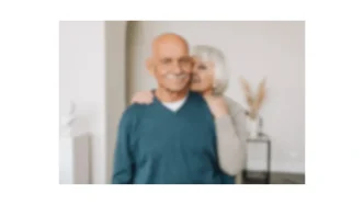 Imagen conceptual desenfocada de una pareja de edad avanzada abrazada en un interior iluminado.